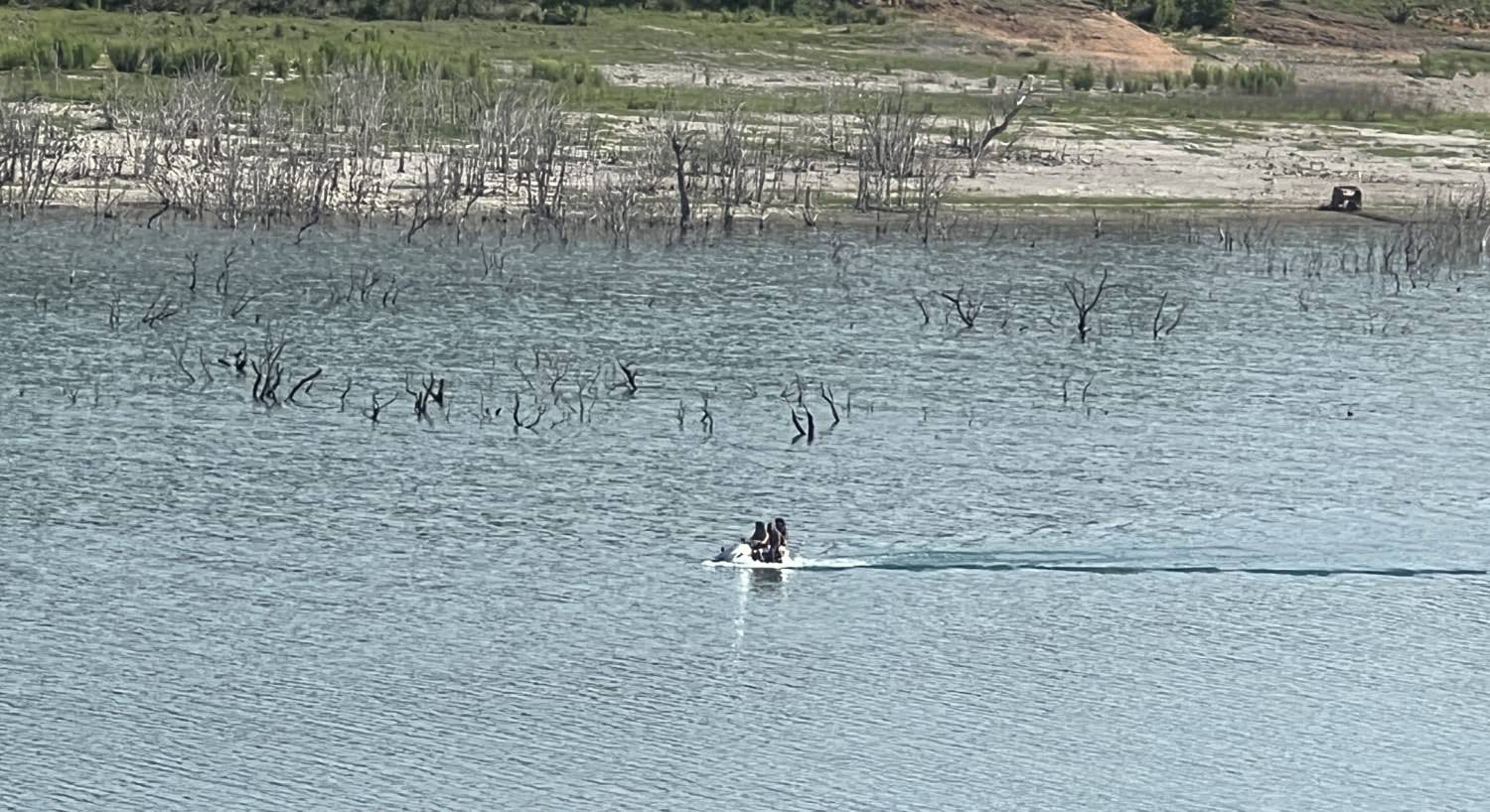 People riding on a jet ski with the shore line in the background