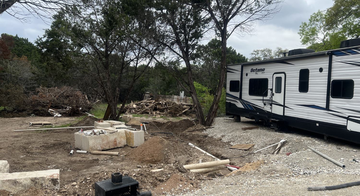 White and gray RV camper set up as a vacation rental next to a spot under construction