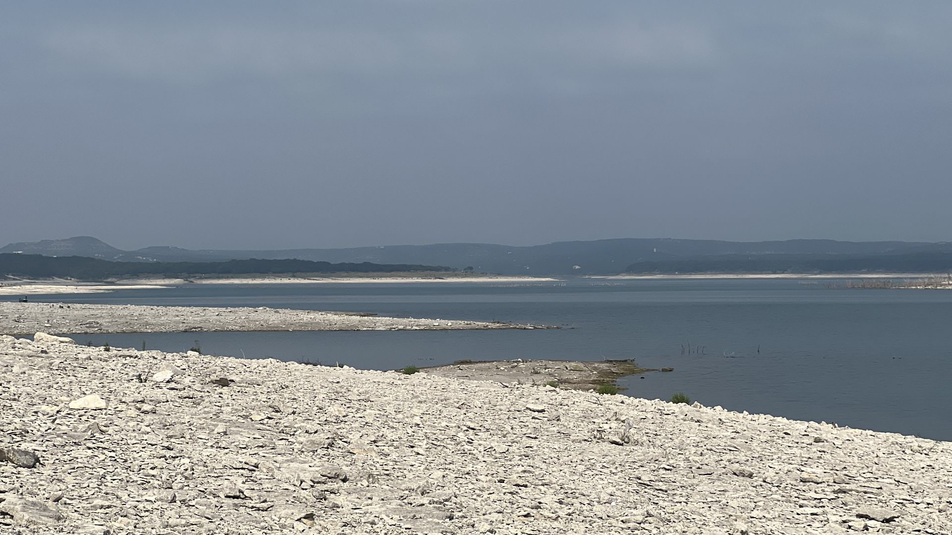 Body of water surrounded by rocky shores with rolling hills in the background