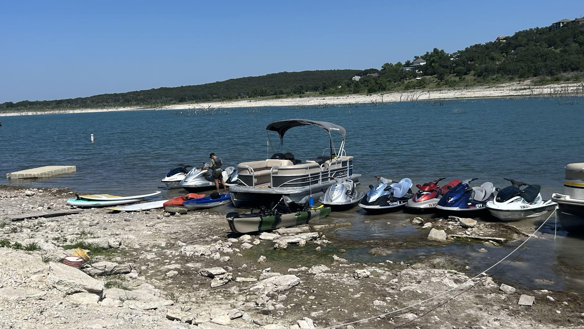 Multiple boats and jet skis docked on the shore