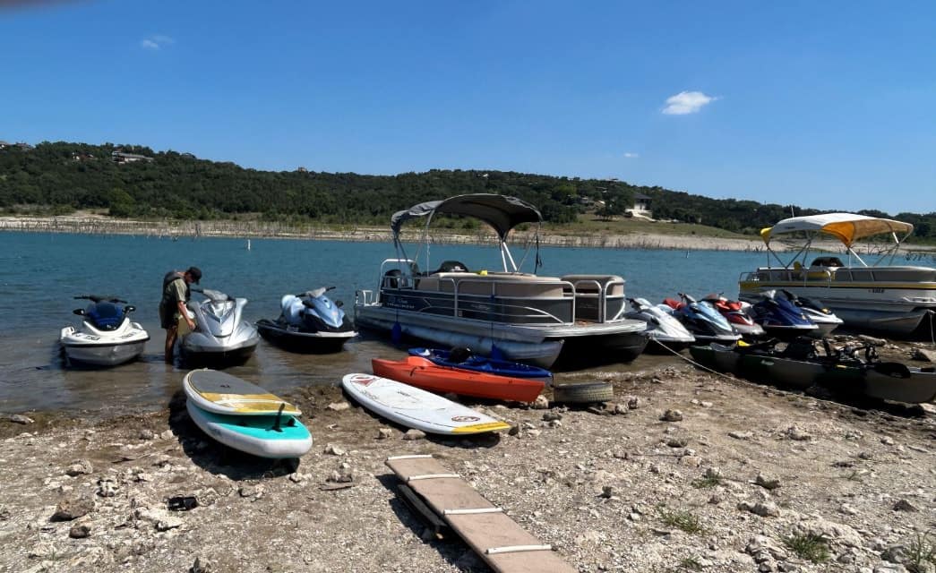 Multiple boats and jet skis docked on the shore