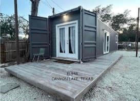 Converted shipping container into tiny home, painted gray with white trim