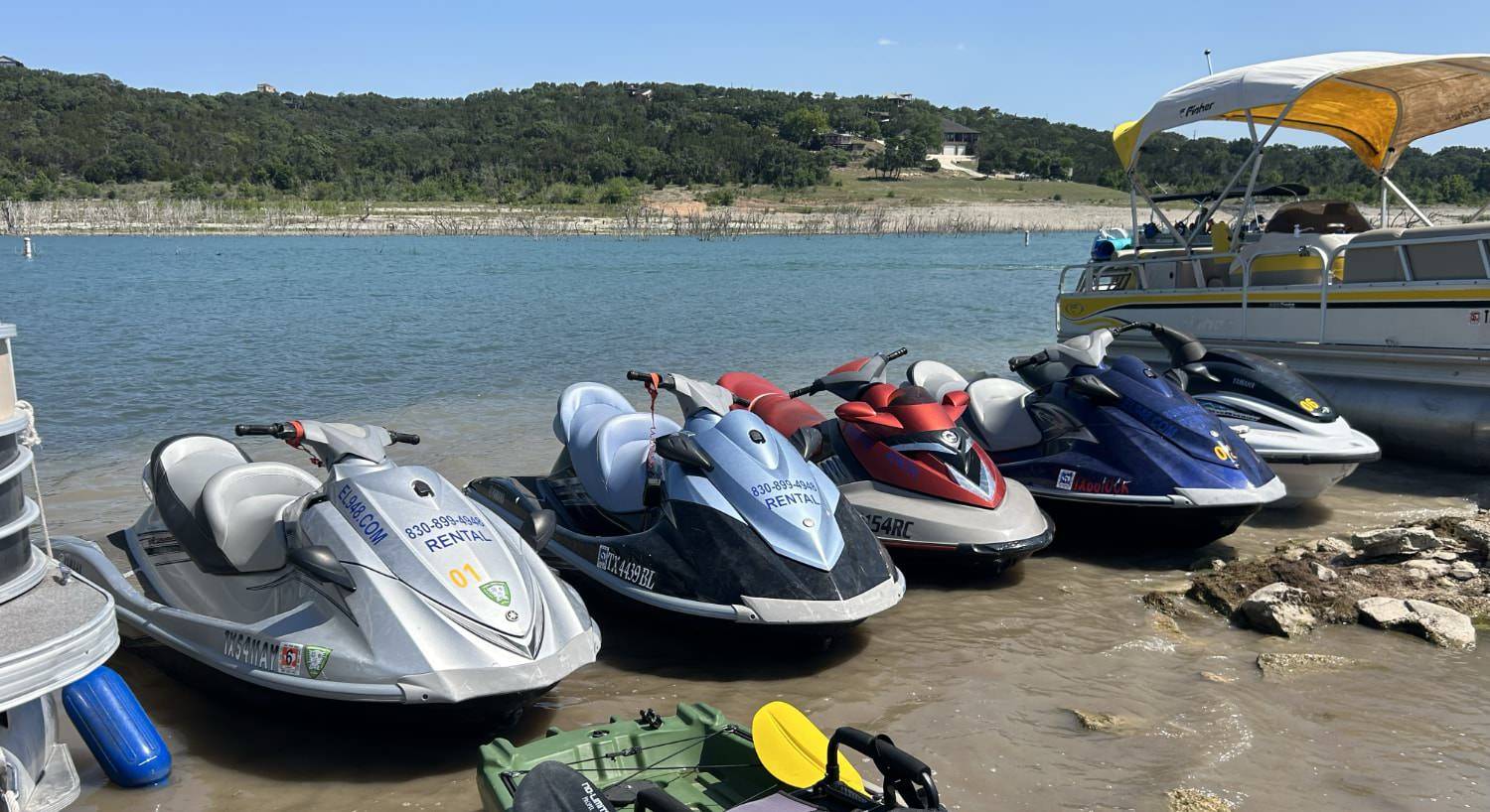 Multiple boats and jet skis docked on the shore